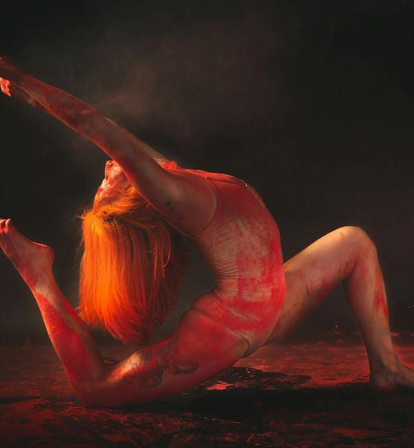 Silhouette of a person in a dynamic yoga pose against a bright background.